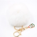 Détail d'un porte-clés pompon blanc avec un pendentif festif en forme de sapin de Noël - Blanc