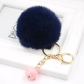Detail of dark blue plush faux fur keychain with golden lobster clasp and pink bell accent - Navy Blue