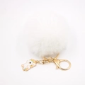 Détail d'un pompon en fausse fourrure blanche avec clip doré et breloque licorne émaillée - Porte-clés Licorne / Blanc