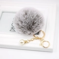 Close-up of fluffy grey pompom keychain with gold chain, lobster clasp and white pearl - Two-tone Grey