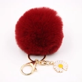 Détail du porte-clés pompon rouge foncé en fausse fourrure avec fermoir doré et marguerite - Bordeaux