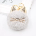 Close-up of a fluffy grey cat pom pom keychain with gold whiskers and glitter ears - Light Gray