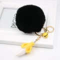 Close-up of black plush pom pom keychain with gold ring and yellow banana charm - Black