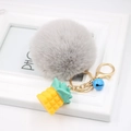 Detail of grey fluffy pompom keychain with yellow pineapple charm and blue bell accent - Light Gray
