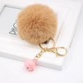 Detail of light brown faux rabbit fur pom pom keychain with gold clasp and pink bell charm - Khaki