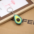 Kreativer 3D-Avocado-Frucht-Schlüsselanhänger mit Silberring auf dekorativem Hintergrund - Avocado