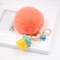 Detail of pink faux fur pompom keychain with golden pineapple charm and blue bell - Orange Red