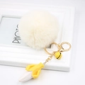 Detail view of plush banana keychain with faux fur ball, golden clasp, and yellow bell - Off-white