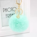 Detail view of a mint green plush pom pom keychain with golden snowflake metal pendant - Mint Green