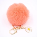 Vue détaillée du porte-clés pompon orange corail avec fermoir doré et fleur marguerite - Rouge Orangé