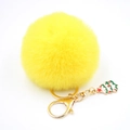 Vue détaillée du porte-clés pompon jaune avec pendentif de sapin de Noël en émail doré - Jaune