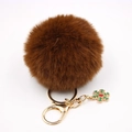 Détail du porte-clés pompon marron café avec fermoir doré et pendentif flocon de neige vert - Marron