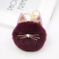 Close-up of fluffy dark purple cat keychain with gold metal ears and whiskers detail - Fuschia