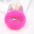 Detailed macro shot of a fluffy pink cat pompom keychain with golden metal whiskers - Rose Red