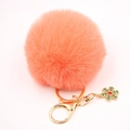Détail d'un porte-clés pompon en fausse fourrure rose avec fermoir doré et flocon de neige - Rouge Orangé
