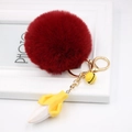 Detailed close-up of a burgundy faux fur pompom keychain with a resin banana charm - Burgundy