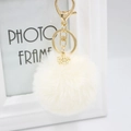 Close-up of cream faux fur keychain with golden alloy snowflake pendant and lobster clasp - Off White
