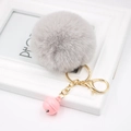 Detail of soft grey faux fur pompom keychain with golden clasp and pink bell accent - Light Gray