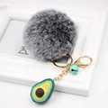 Detail of avocado plush keychain with grey pompom, gold metal clip, and small blue bell - Avocado Keychain / Two-tone Black
