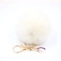 Detail of fluffy white pompom keychain with golden clasp and unicorn enamel charm - Small Unicorn Keychain / Off White
