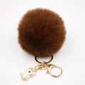 Vue détaillée du pompon en fausse fourrure marron foncé avec breloque licorne et métal doré - Porte-clés Licorne / Marron