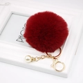 Detail of burgundy faux fur pompom keychain with gold lobster clasp and pearl charm - Burgundy