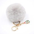 Détail d'un porte-clés en fausse fourrure grise avec un pendentif sapin de Noël vert - Gris clair