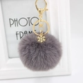 Detailed view of gray plush pompom keychain with golden snowflake charm and lobster clasp - Dark Gray