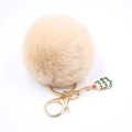 Détail d'un porte-clés pompon en fausse fourrure beige avec fermoir doré et sapin de Noël - Nu