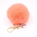 Macro detail of an orange faux fur pompom keychain with a white unicorn charm and gold clasp - Small Unicorn Keychain / Orange Red