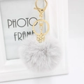 Detail of light grey faux fur pom pom keychain with a gold snowflake charm and lobster clasp - Light Gray