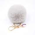 Detail of grey faux fur pom pom keychain with gold unicorn charm on white background - Small Unicorn Keychain / Light Gray