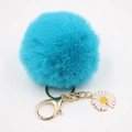 Gros plan sur un porte-clés pompon en fausse fourrure bleu clair avec breloque marguerite - Bleu lac