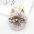 Close-up of cute grey plush cat pompom keychain with golden metal whiskers and heart nose - Two-tone Grey