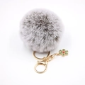 Détail d'un pompon en fausse fourrure grise avec breloque flocon dorée et cristal rouge - Gris bicolore