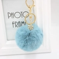 Close-up of light blue fluffy keychain with golden snowflake charm and metal lobster clasp - Teal