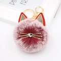 Detailed close-up of fluffy pink ombre cat pompom keychain with golden metal whiskers - Dual-color Red