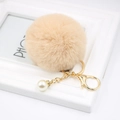 Detail of soft beige faux fur pompom keychain with gold lobster clasp and pearl - Nude