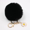 Vue détaillée du porte-clés pompon noir avec fermoir doré et charm marguerite blanche - Noir