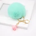 Gros plan sur un porte-clés pompon vert menthe avec mousqueton doré et clochette rose - Vert Menthe