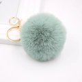 Detail of mint green faux fur pompom keychain with shiny gold metal ring and lobster clasp - Matcha Green
