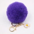 Vue détaillée d'un porte-clés pompon violet avec un pendentif marguerite émaillé - Violet foncé