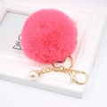 Detailed close-up of pink faux fur keychain with gold ring and elegant pearl charm - Watermelon red