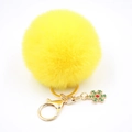 Vue détaillée d'un porte-clés pompon jaune avec pendentif flocon doré sur fond blanc pur - Jaune