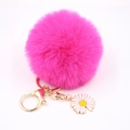 Détail d'un porte-clés pompon en fausse fourrure rose rouge avec fermoir doré et marguerite - Rose rouge