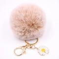 Détail d'un pompon duveteux abricot avec fermoir doré et pendentif marguerite - Khaki mélangé
