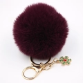Détail d'un porte-clés pompon bordeaux avec pendentif flocon doré pour sacs d'hiver - Fuchsia