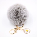 Détail d'un porte-clés pompon gris avec fermoir doré et pendentif fleur de marguerite blanche - Bicolore Gris