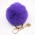 Détail d'un porte-clés en fourrure violette avec fermoir doré et pendentif flocon vert - Violet foncé