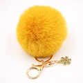 Détail d'un porte-clés pompon en fausse fourrure jaune avec flocon en émail vert et strass - Orange
